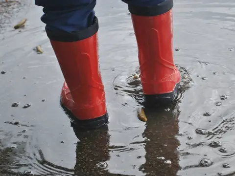Red rubber boots standing in shallow water