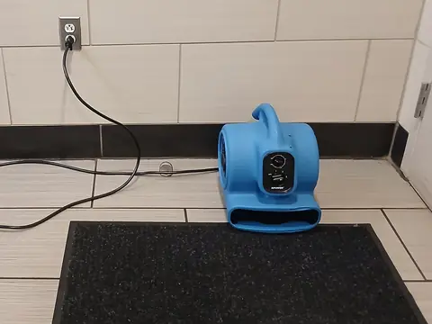 An air mover blowing across a tiled floor to dry it