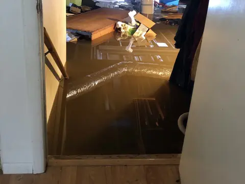 Floodwater filling a basement at the foot of the stairs