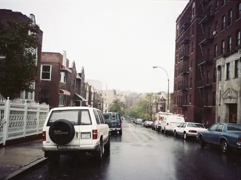 A rain-wet street of apartment buildings on Loring Place South in the Bronx