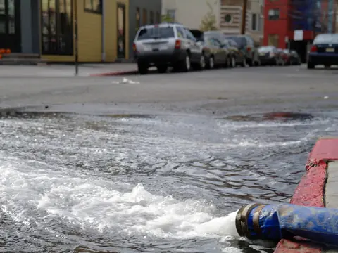 A hose pumping water out of a basement into a city street