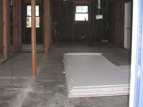 A gutted house with the wall board removed and new sheets stacked on the floor
