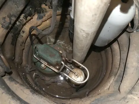 A sump pump sitting in its pit in a basement floor